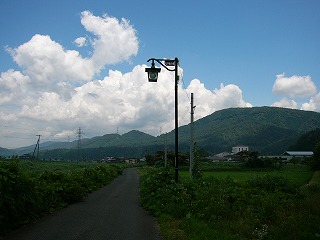 緑の中を縫う一本の小径。洒落た街灯一本。奥の方に優しい山容。上の写真との続き。