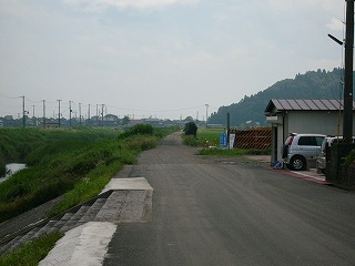 うす曇の空に草におおわれた革、田んぼ、砂利道。