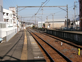 細い鉄骨の門形架線柱の並ぶホームからの風景。