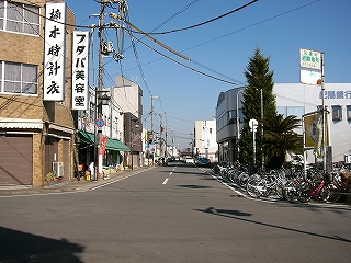 両脇に二階建ての建物の並ぶに車線の通り。自動車は一台も走っていない。