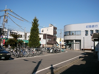 三角の緑の木、自転車、二階建ての新しい銀行の建物。