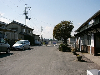 左手に住宅の裏手、そして駅前の敷地、そして右手に駅舎入口。
