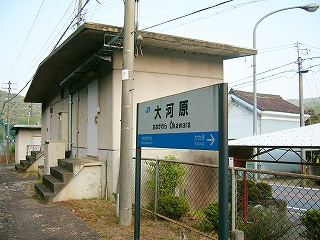 短い階段の先に扉のついている、窓のない少し古いコンクリト製の信号機室とホームに二本足で立つ駅名標を斜めに見て。