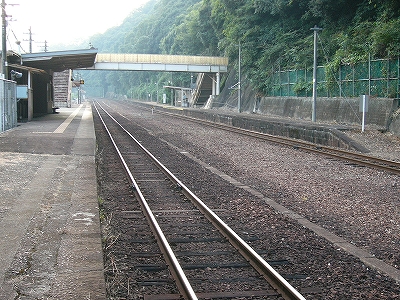 右にこんもりした山肌の緑、そして中線を取り払った余裕のある2線の停車場、それを跨ぐ簡単な跨線橋、左には下り線ホームと駅舎が下り線のホームにまで伸ばした屋根