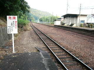 左に「危険」の看板、右に伸び行く線路内、右奥には隣のホームの端にある信号機室が写っている。