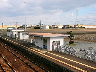床面積より広い陸屋根を持つ簡易駅舎。奥のほうには冬の田が広がる。