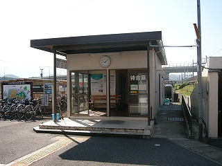 平たい屋根が入口よりも手前にまで延長されて、入口前に軒を作っているプレハブのような待合室。