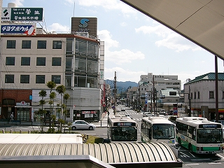 まっすぐ伸びる二車線の賑やかな通りと駅前の古いビルを見下ろして。