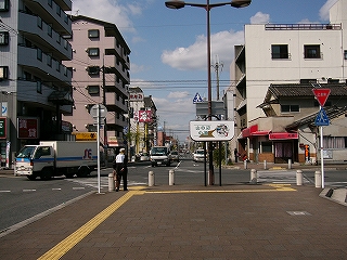 ロータリーを二つに分ける歩道の突端部から見た二車線の道路を眺めとおして。