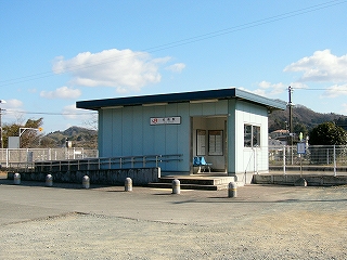 水色の外壁に青の陸屋根の簡易な駅舎。スロープがついている。