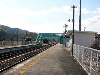 幅広いホームから。遠くにエメラルド色の跨線橋。