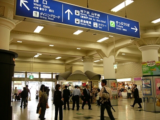 青地に白い字の案内板とコンコースの風景。