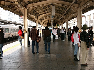 Ｗ型の上屋のあるホーム中央にホームと平行方向を向いて。多くの人がいる。