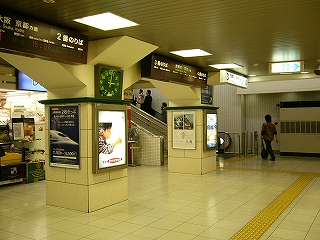 低い柱とクリーム色の床、突き当たり左手に階段上り口。