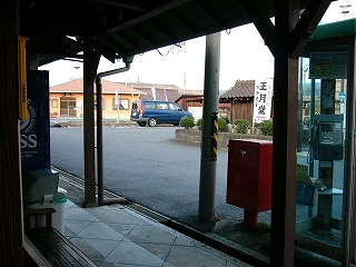 駅舎から出てすぐ左を見たときのようす。軒下に接近して設置されてある電話ボックス、ポストを見る。また、少しの空間からは駅前の小さなロータリーの中心が見えている。