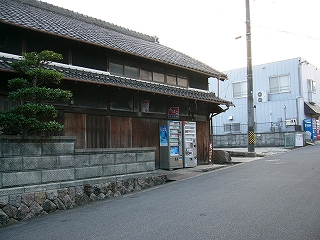 すべての木戸が閉じられた家の一階部分。自動販売機があり、軒下からは小さな看板が吊られ、お店らしかった。