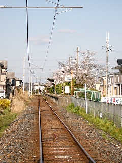 まっすぐに伸びる鉄路。遠くの右手にホーム。