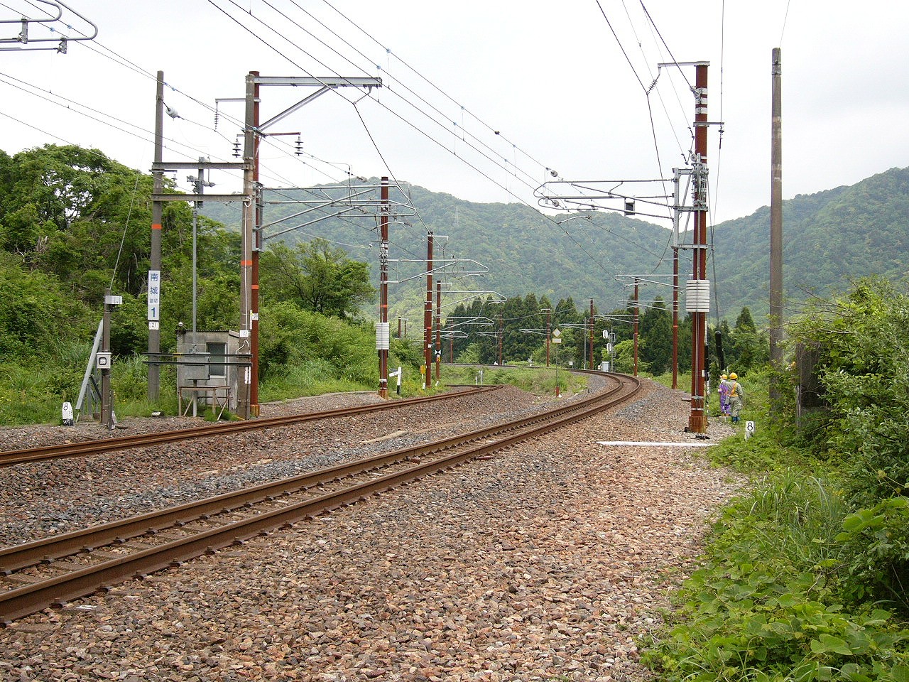 2線は先のほうで左カーブ。奥にはまた山。両端は低木と草むら。