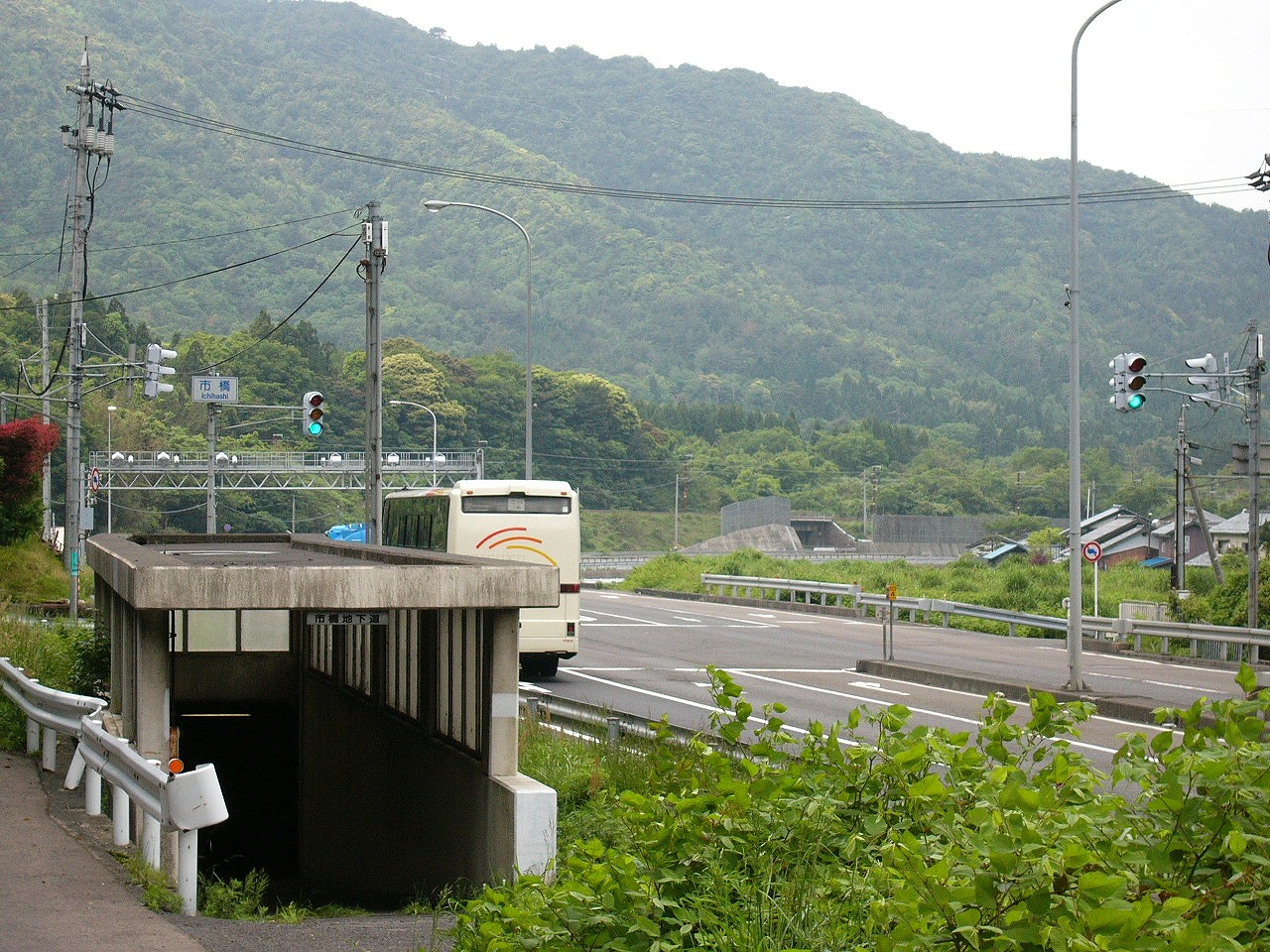 遠くにカーブした道。背景には400m級の里山の山並み