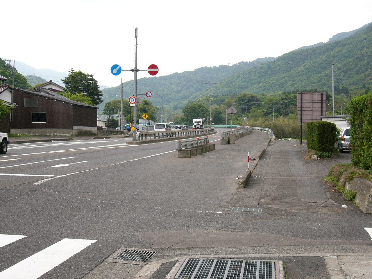 山に囲まれた国道。中央分離帯はガードが設けられ、歩道は寒々と広々としている。
