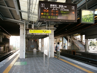 タイルに覆われた床面のホームと一部半透明になった上屋とそこから吊り下げられた発車案内板。奥の方は橋上コンコースの下にあたり、少し暗い。