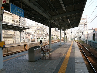 中央に個掛けの椅子とゴミ箱のあるホーム。少し先の方で上屋は無くなっている。