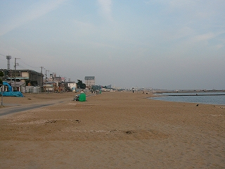 砂浜。ずっと遠くに少し高い建物の群れ。