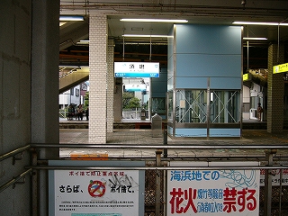 フェンスの向こうにホームと駅名標が見える。