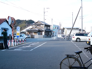 小さめの駐車場。道を挟んで左奥に民家。