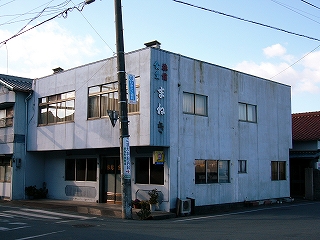 古びた外壁塗装のコンクリートの小さな直方体の建物。