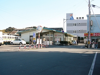 駅舎から離れて右斜めに見て。左脇に駅舎前の駐車場に接する道は広いが、駅舎に差し掛かるあたりから急に狭くなっている。その手前で右手に折れれば歓迎の門。
