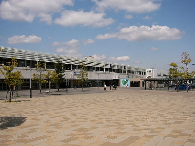 広場と高架駅。ところどころ木々が植えられている。