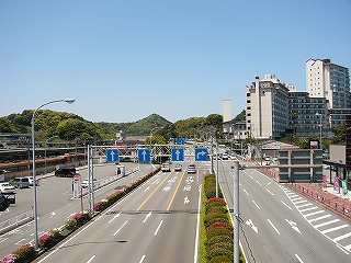 広い道路。向こうのほうに低いが鮮やかな緑の山々が見える。