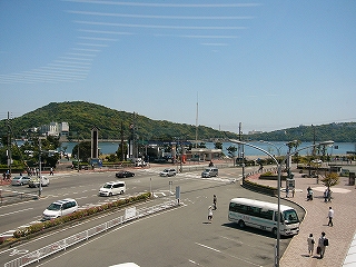 広いバス駐車場と道路、そして海、山。