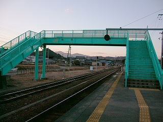 夕暮れ空に浮かぶ緑色の堂々たる無蓋跨線橋。