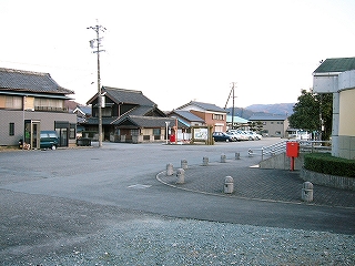 民家に囲まれたような広いアスファルトの敷地。駅前に出てくる細道が、家と家の間に見えている。