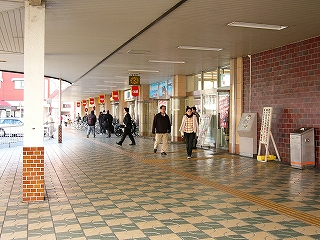 右手に駅舎入口の扉群。上には駅舎から平らに延びてくる屋根がある。