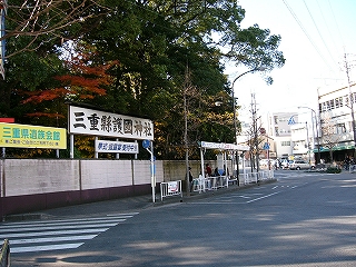 左手に塀があり、そこから林が覗いている。塀の上には「三重縣護国神社」の横長の看板も立てられている。