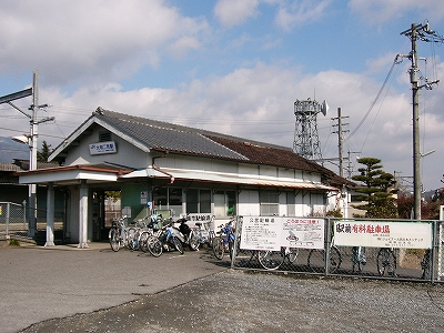 妻面に入口のある木造瓦葺の白い駅舎。