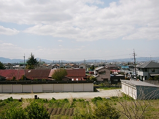 盆地に家並みが広がる。遠くに低い山々。