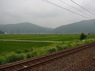 広々とした田んぼ。その向こうに大きな集落。そしてその向こうには山が迫っている。