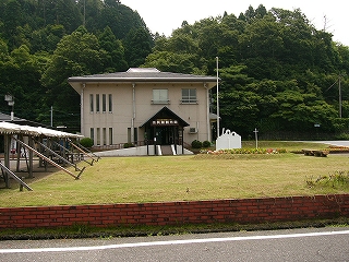 手前に芝生。奥に建物。その奥はすぐに山手。