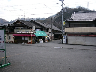 広いアスファルトの敷地の向こうに民家。